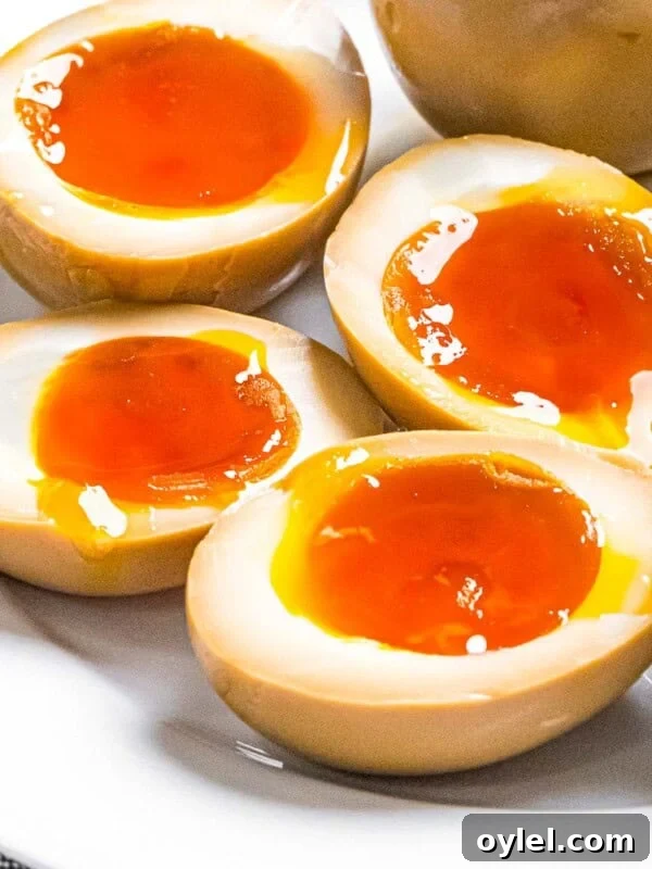 Ramen eggs marinated in soy sauce cut in half to reveal soft boiled eggs with runny yolks.