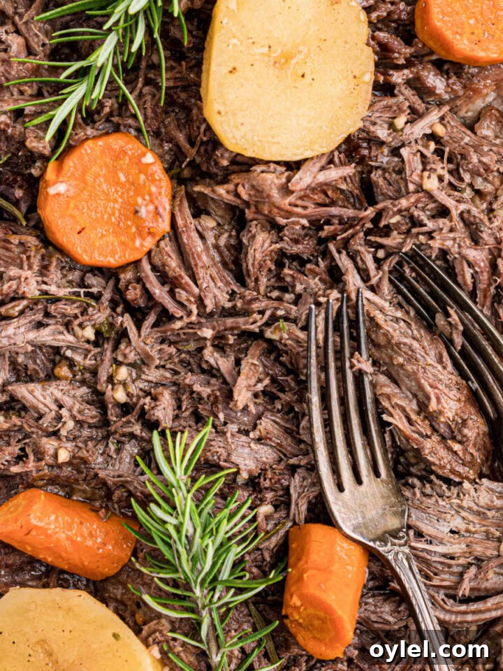 A close up of tri tip roast with potatoes and carrots and a pair of forks sitting in the dish.