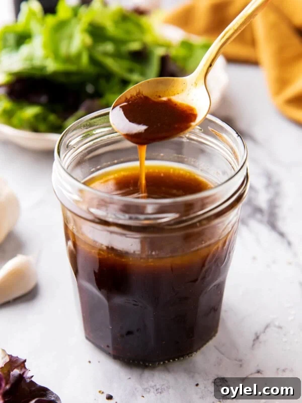 Maple Vinaigrette Recipe for Salads 10 Someone scooping a spoon of balsamic vinaigrette dressing out of of a salad dressing jar