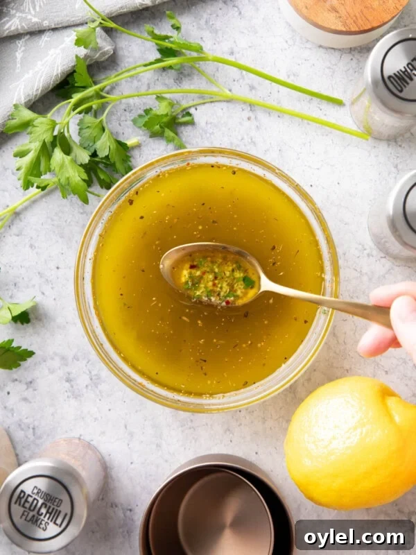 Maple Vinaigrette Recipe for Salads 9 Spooning this Italian Dressing Recipe from a mixing bowl to showcase the ingredients, including herbs, olive oil, lemon juice, and more.