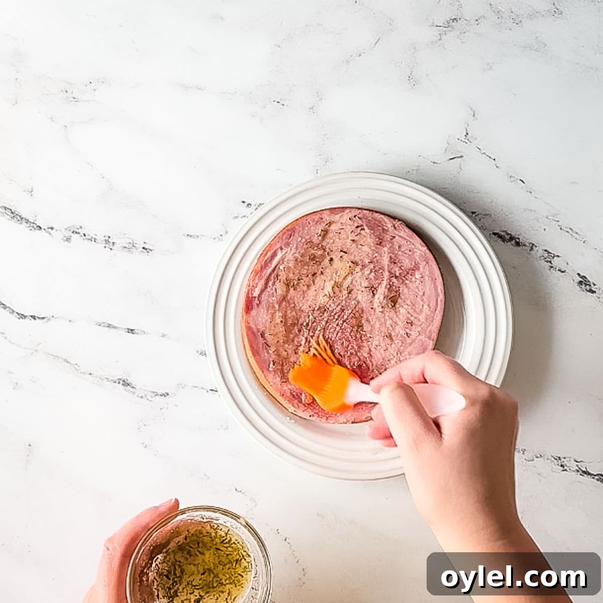brushing ham steak with brown sugar glaze.