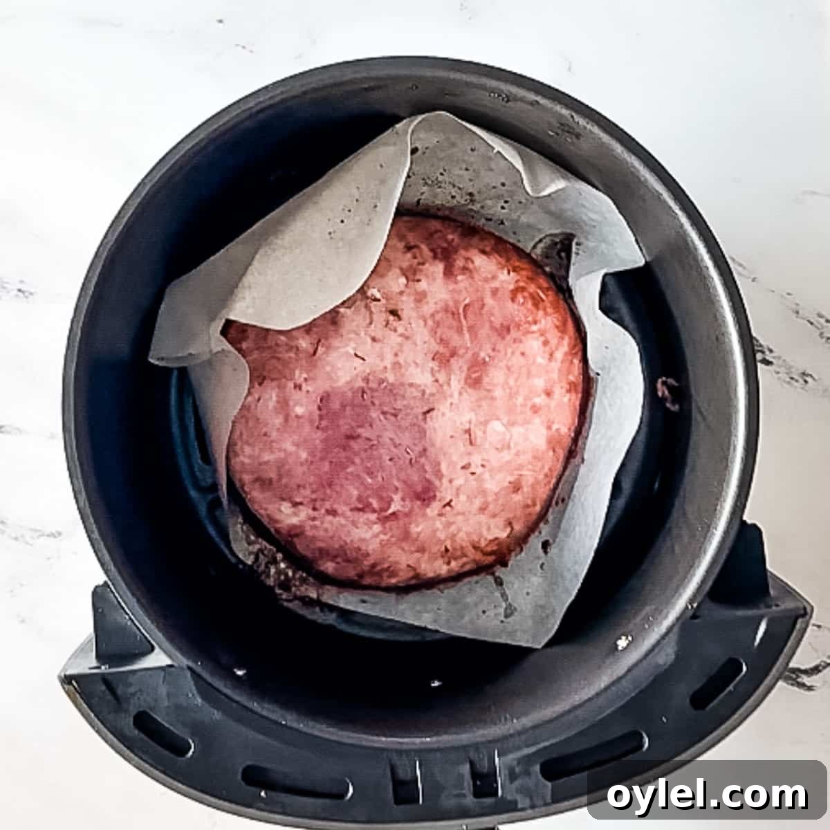 half-cooked air fryer ham steak in air fryer basket.