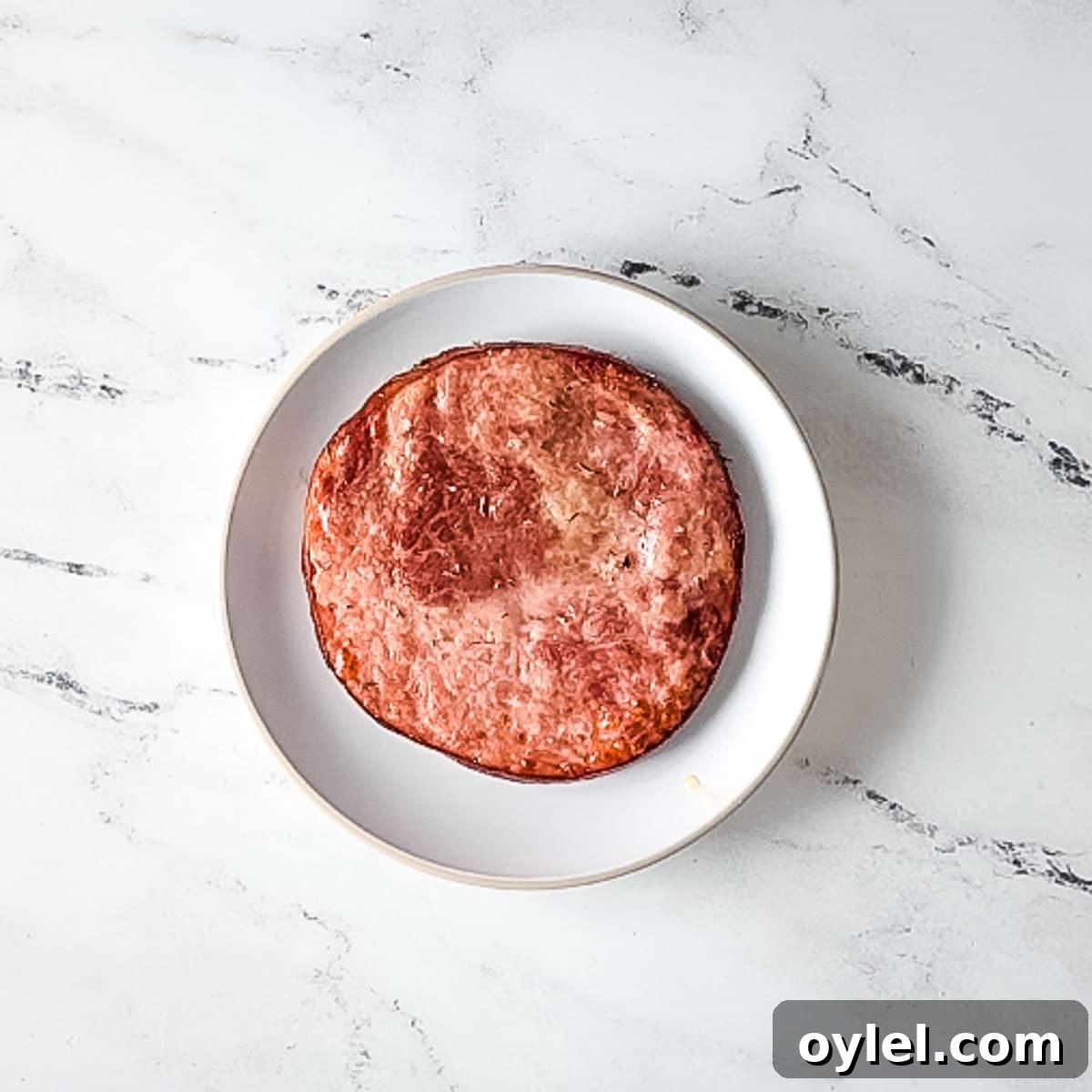 finished air fryer ham steak on a white plate.