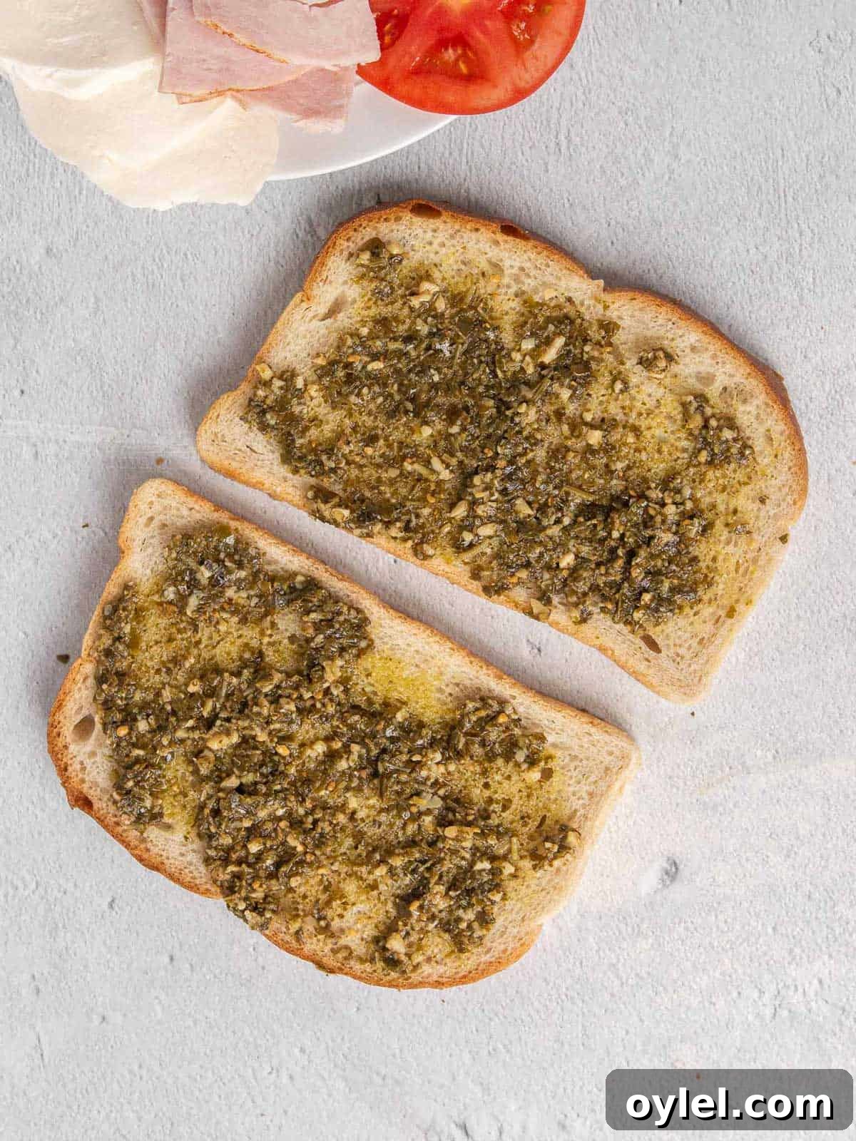 Grilled Turkey Pesto and Mozzarella Sandwich Recipe 4 Two pieces of sourdough bread with pesto layered across the top.