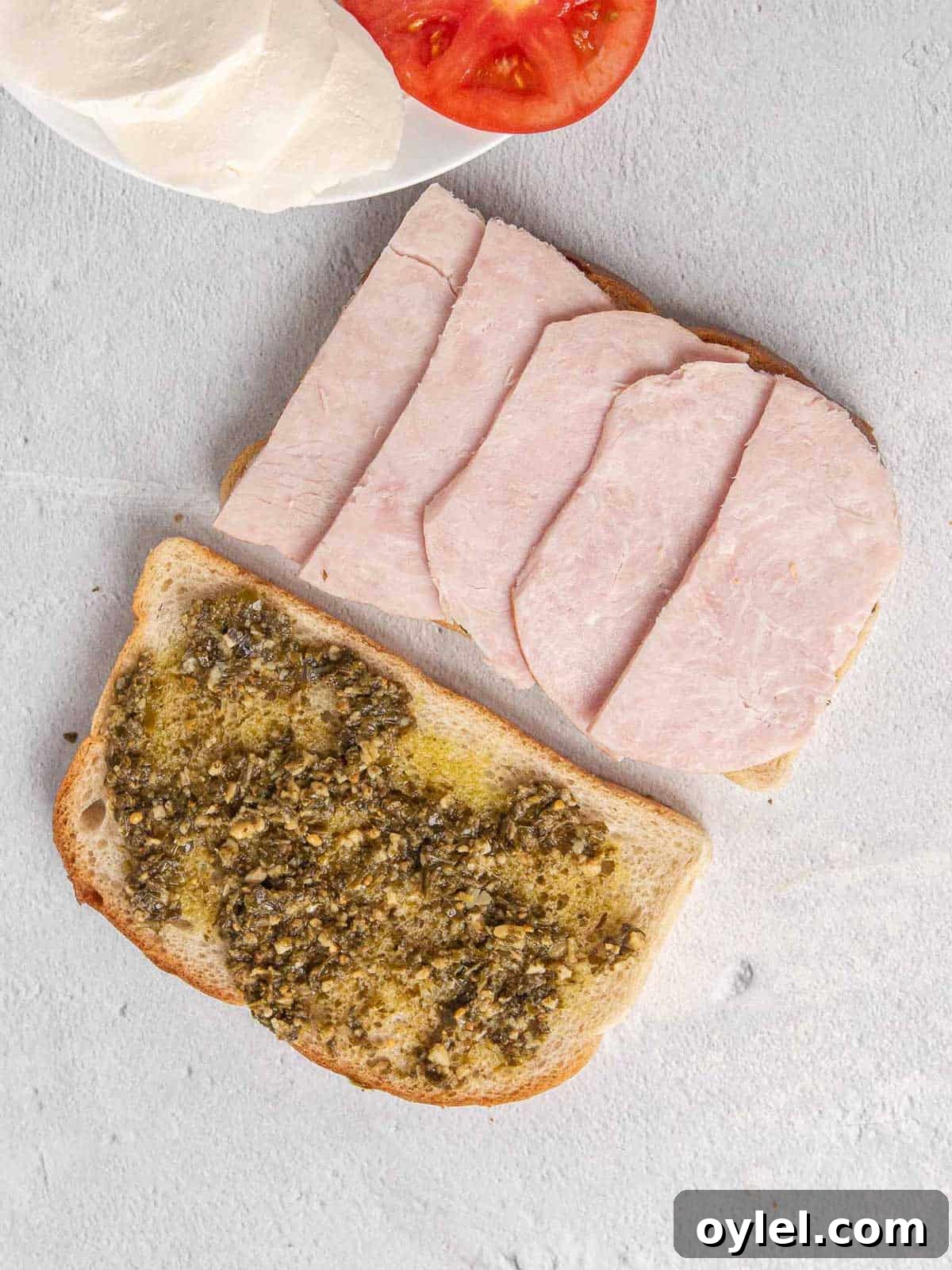 Grilled Turkey Pesto and Mozzarella Sandwich Recipe 5 Two pieces of sourdough bread with pesto layered across the top. One one slice of bread, thick slices of turkey are layered on top.
