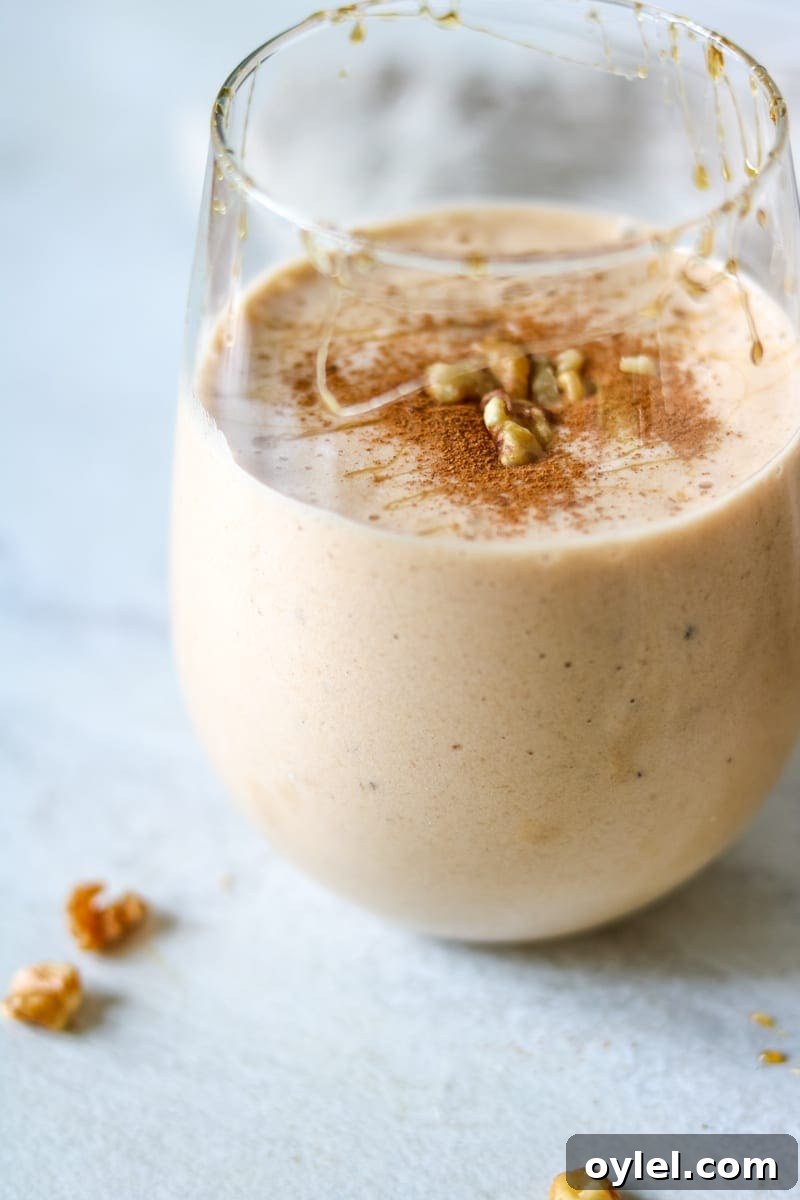 Vegan Sweet Potato Pie Smoothie in clear glass with cinnamon, maple and walnuts sprinkled on top.
