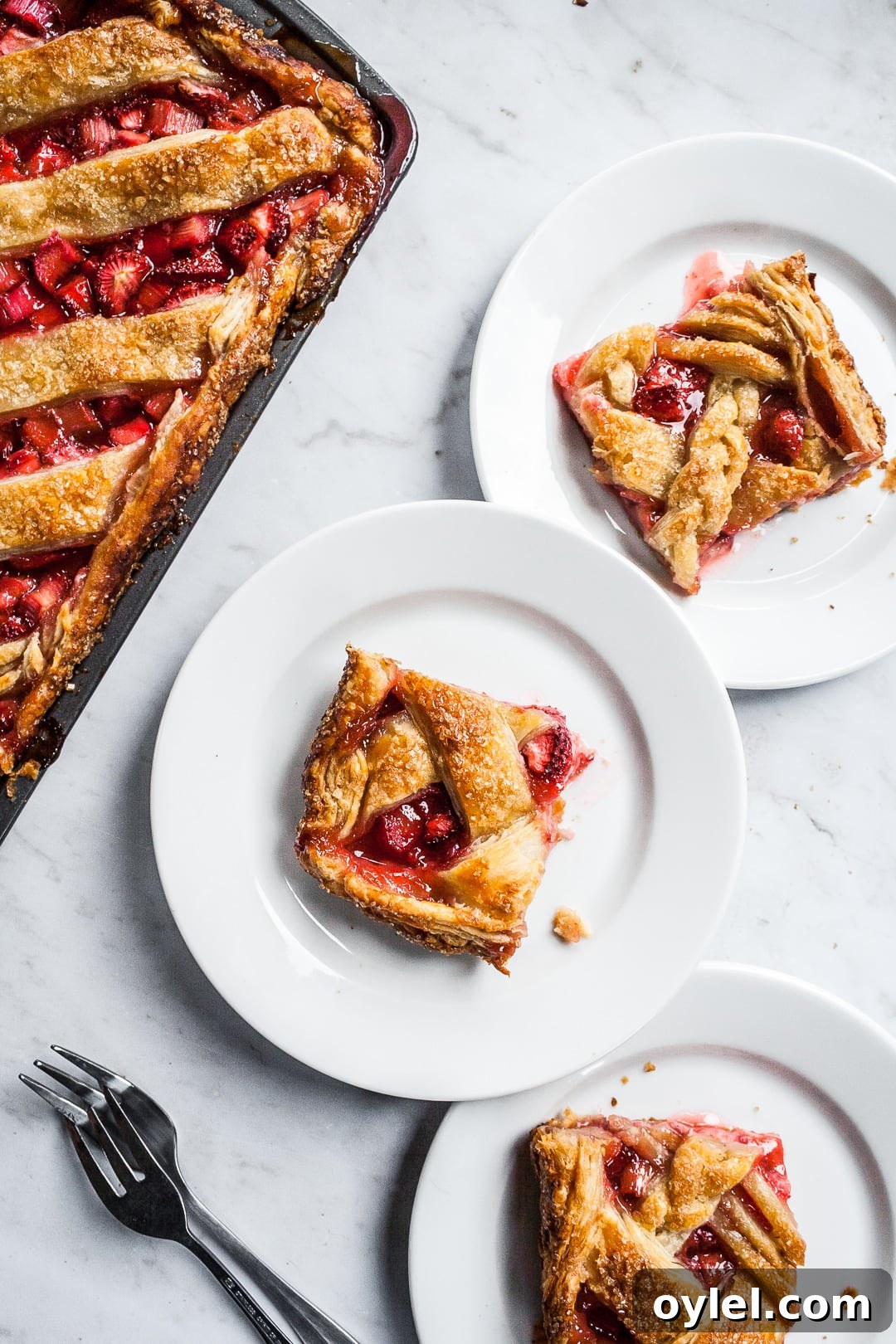Slices of slab pie on white plates next to a sheet pan of slab pie