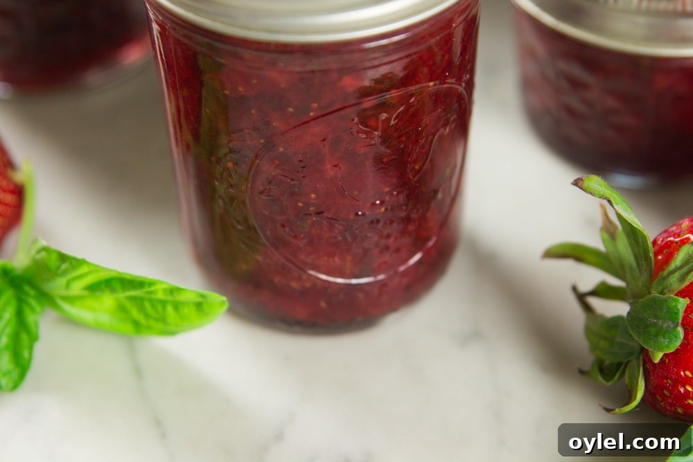 A jar full of strawberry basil preserves on a table.