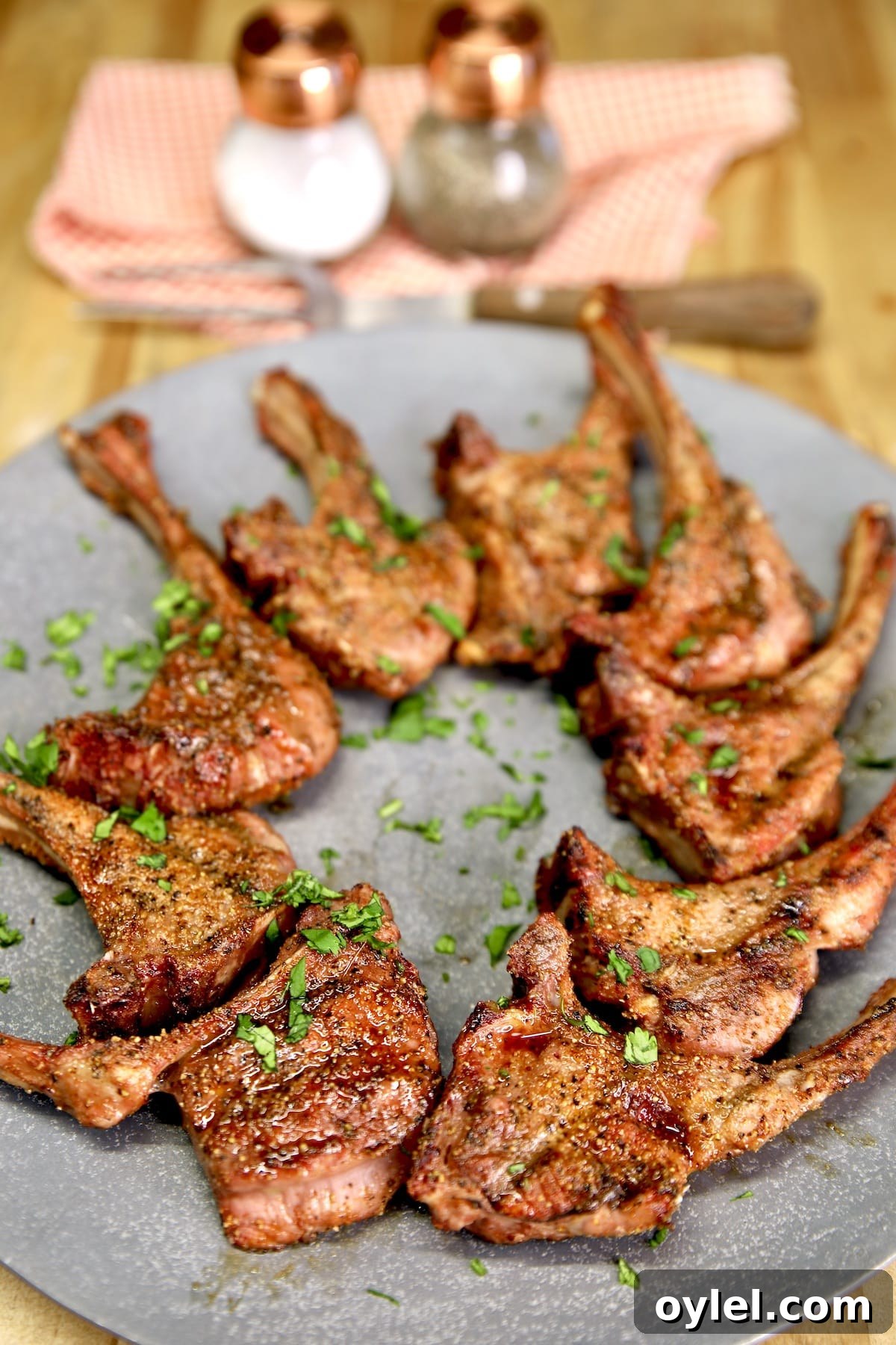 Platter of bone in venison steaks salt and pepper in background.