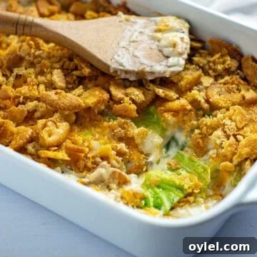 baked casserole in a white oblong dish with one serving removed and wooden spoon sitting on top of casserole