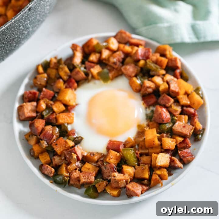 A plate of sweet potato hash with an egg in it and onions and a green napkin behind it.