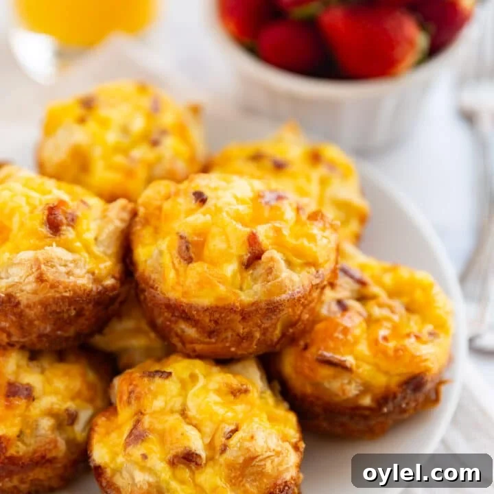 A close up of a bacon egg and cheese muffin on a plate with the other ones.
