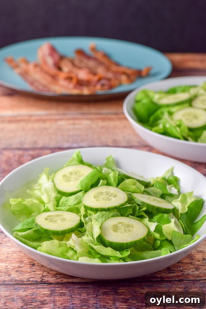 Boston lettuce and cucumber slices with the bacon on the plate in the background