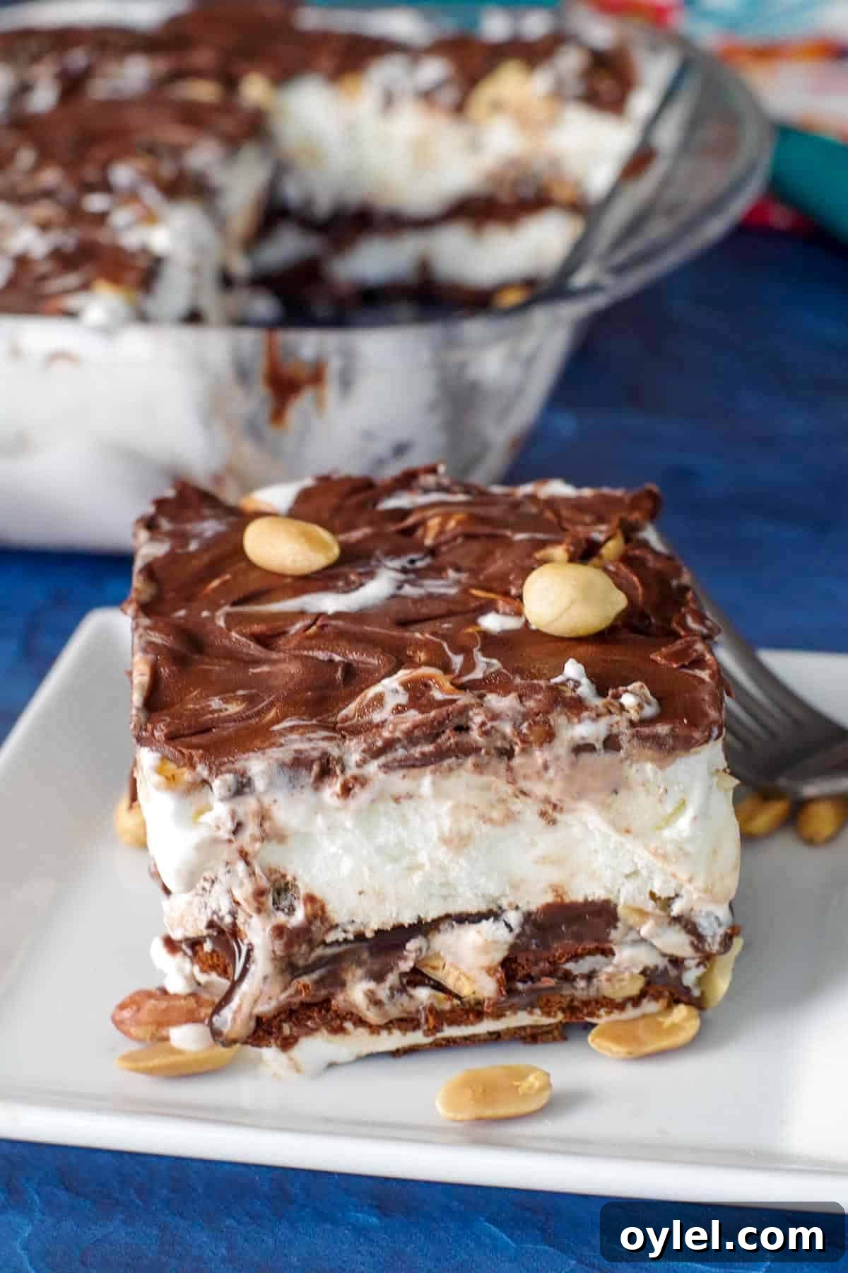 piece of buster bar ice cream cake on white plate with fork and whole glass pan in background