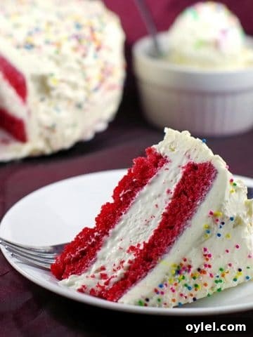 Slice of red velvet ice cream cake with whole cake in the background and a bowl of no churn ice cream