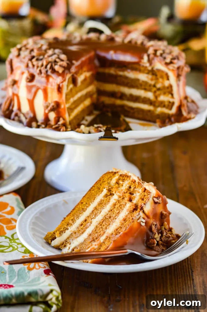 A slice of layered pumpkin cake is served on a white plate with a fork beside it.