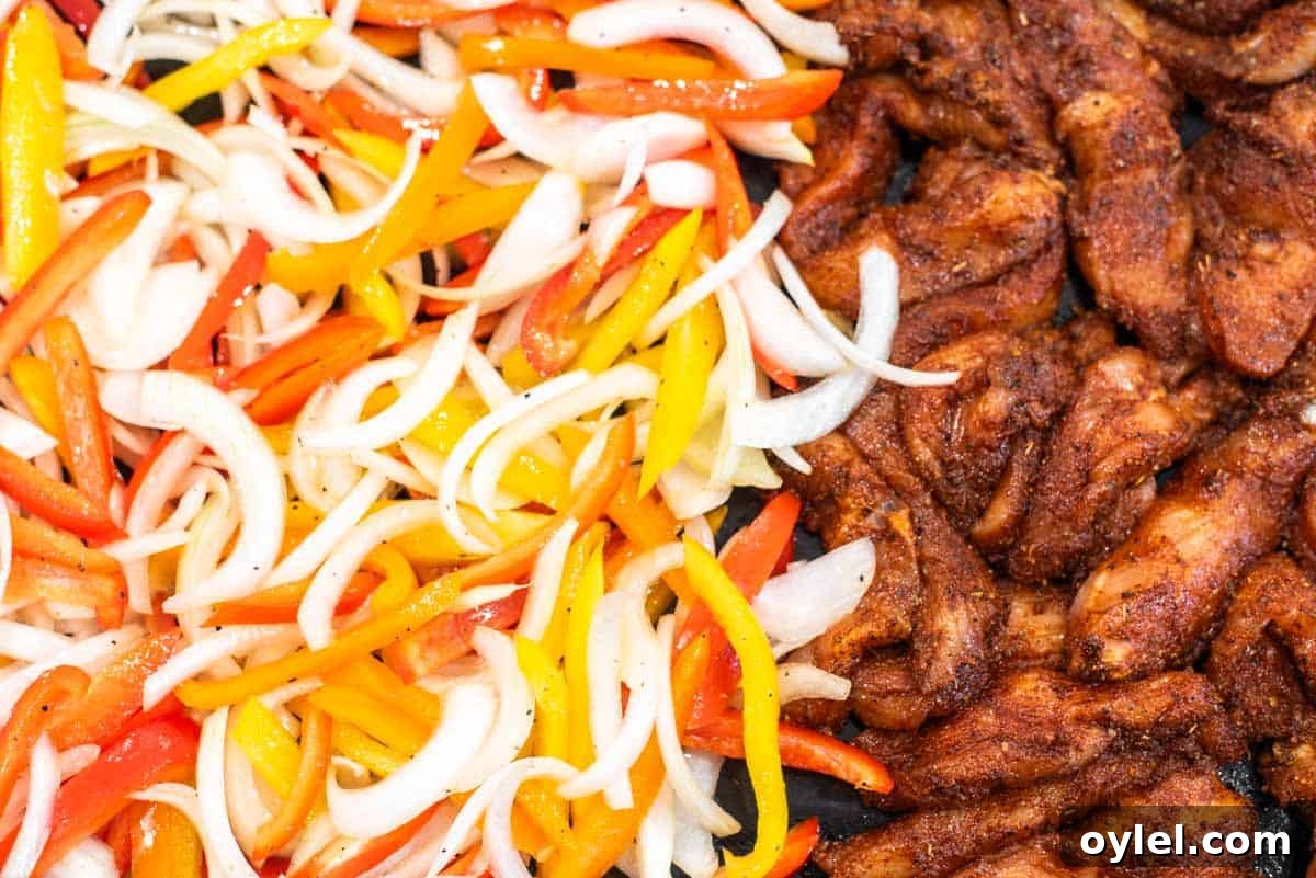 Sheet Pan Chicken Fajitas Recipe with Peppers and Onions 6 Peppers, onions and seasoned chicken in pan.