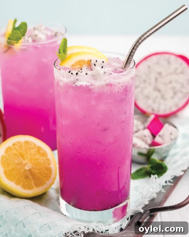Dragon fruit lemonade in a glass with fresh lemon and a metal straw.