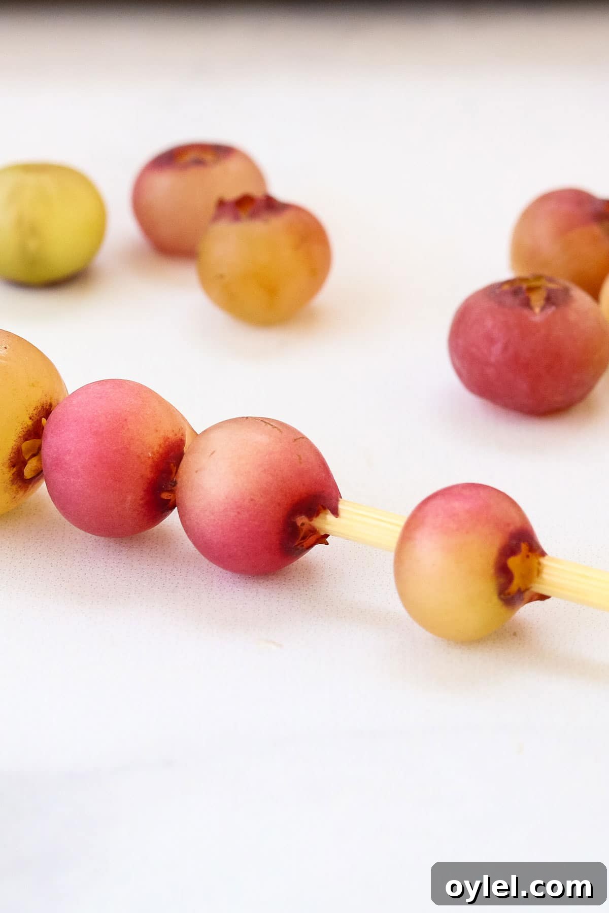 Threading grapes onto skewers to make caterpillar fruit kabobs for kids.