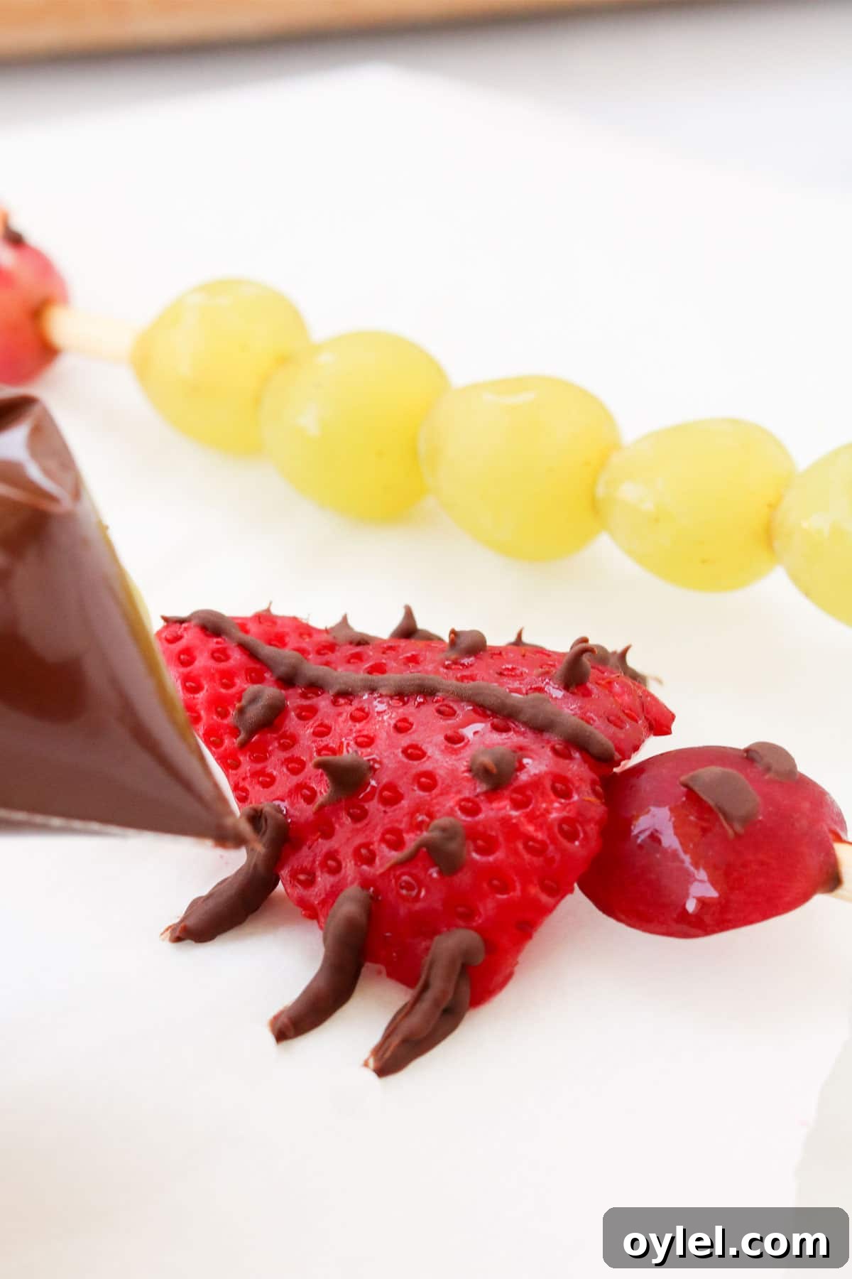 Adding the legs to bug fruit kabobs for kids.