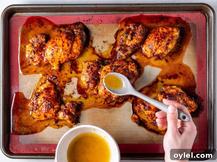 Crispy Roasted Honey-Lime Chicken Thighs 10 Spooning honey lime sauce over roasted chicken thighs on baking sheet during cooking