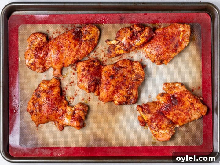 Crispy Roasted Honey-Lime Chicken Thighs 9 Seasoned chili lime chicken thighs arranged on a baking sheet lined with a silicone mat before roasting