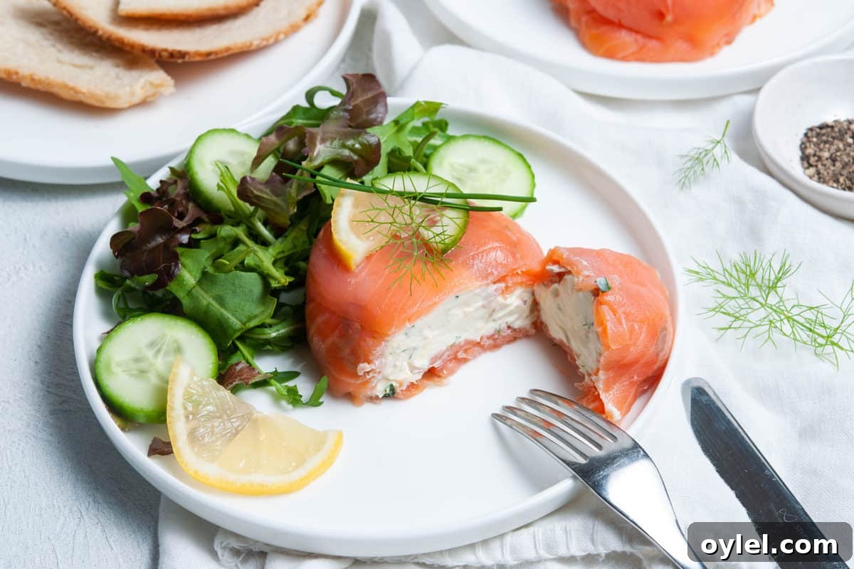 Smoked Salmon Puff Pastry Parcels 7 parcel cut in half, showing cream cheese filling, sitting on a plate with some salad and a wedge of lemon.