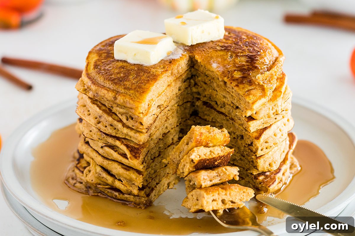 Stack of Pumpkin Pancakes on a plate with a bite on a fork.