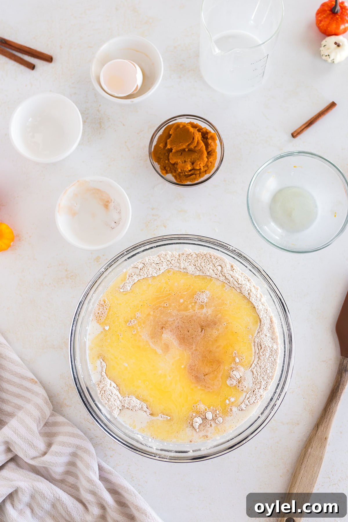Wet ingredients are added to dry ingredients in a mixing bowl.
