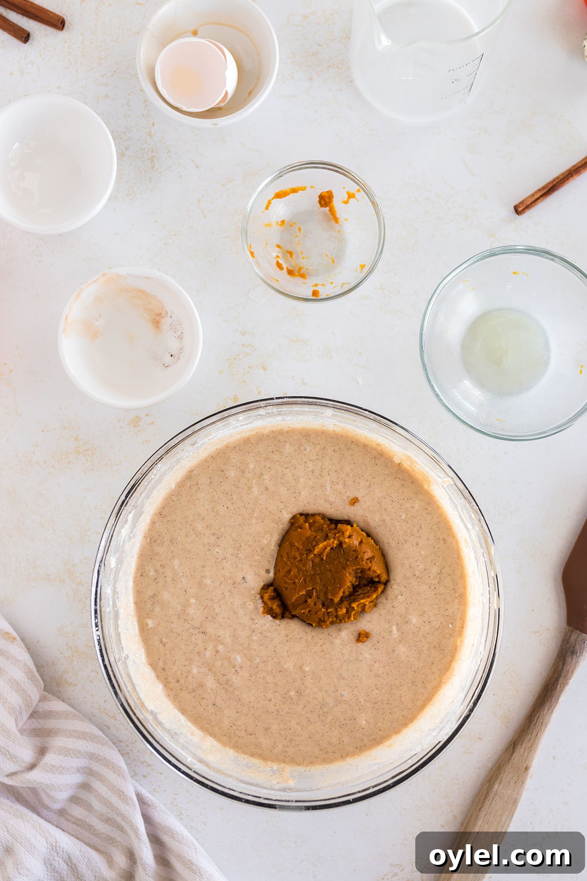 Pureed pumpkin added to pancake batter in mixing bowl.