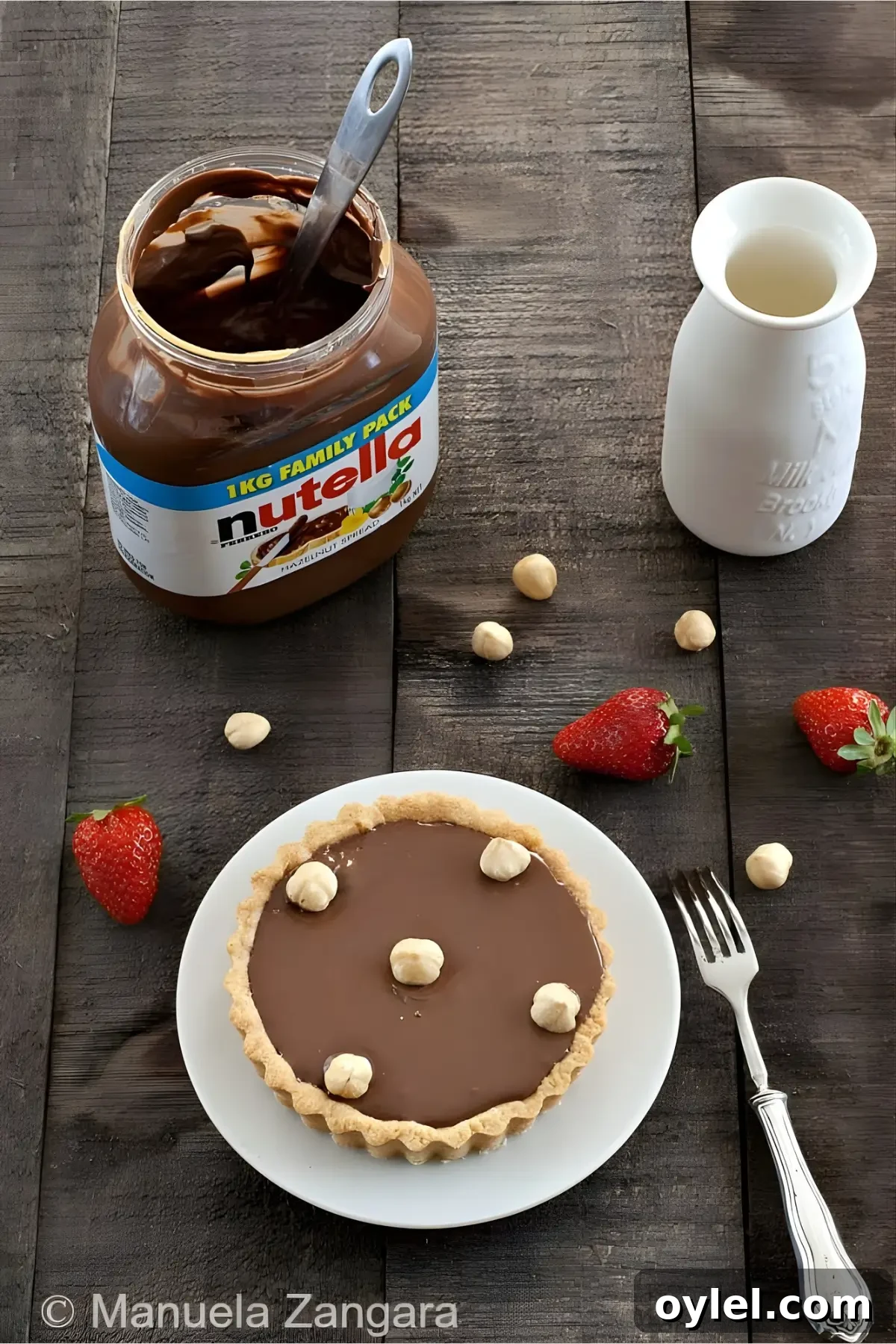 Nutella Tart Recipe: Chocolate-Hazelnut Tartlets 2 Nutella tart on a plate with a jar of Nutella and fresh strawberries.