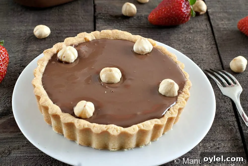 Nutella Tart Recipe: Chocolate-Hazelnut Tartlets 5 Close-up of a Nutella tart topped with whole hazelnuts.