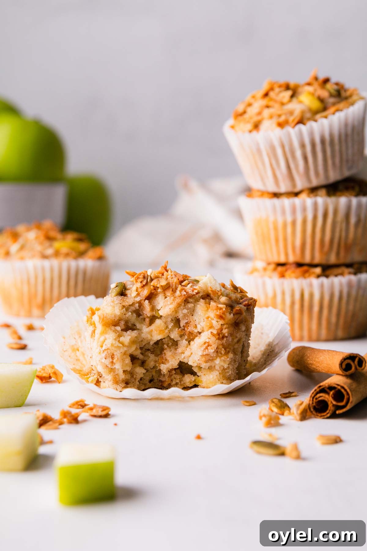 One muffin with a bite taken next to a stack of muffins.