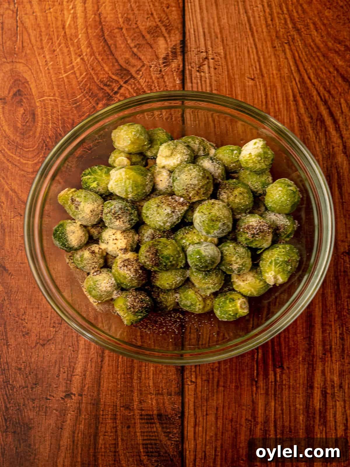 Frozen brussels in a bowl with seasonings.