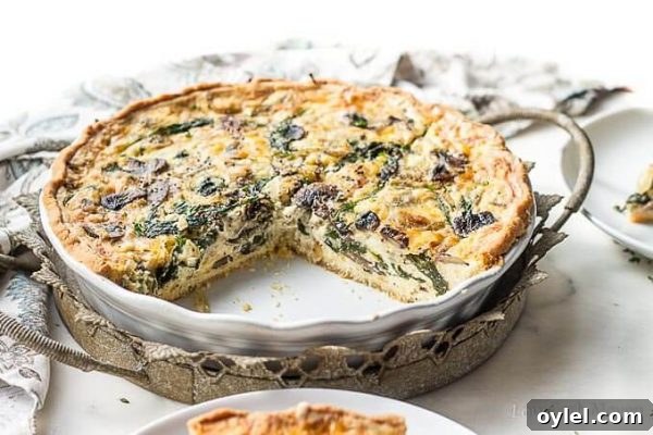Spinach and mushroom quiche in a white quiche dish.