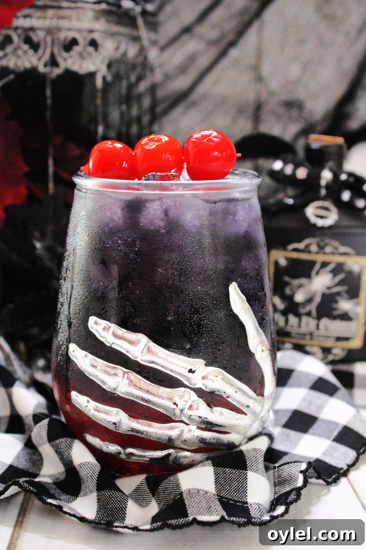 A Halloween glass with a Black Widow drink and cherries on top.