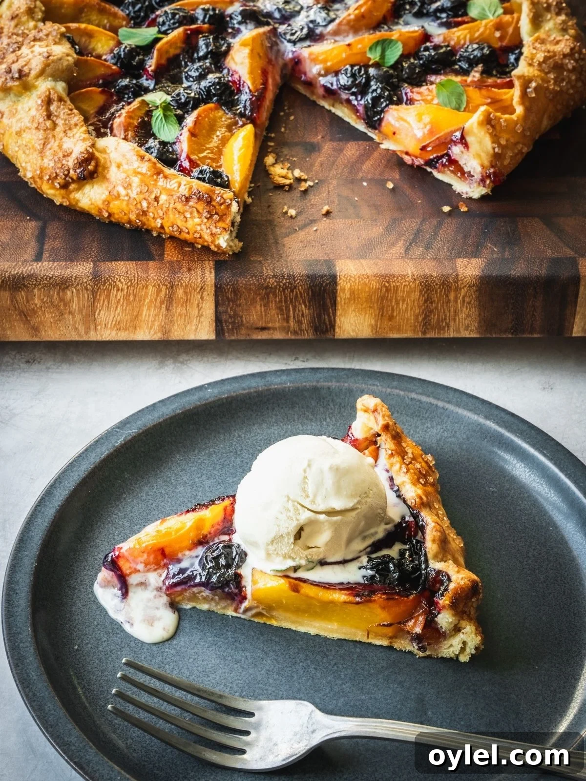Blueberry Peach Galette Recipe with Lime and Brown Sugar 2 Slice of blueberry peach galette on a plate with a scoop of ice cream.