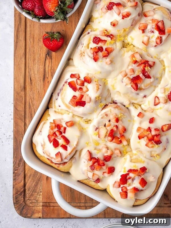 A tray of strawberry cinnamon rolls with cream cheese icing.