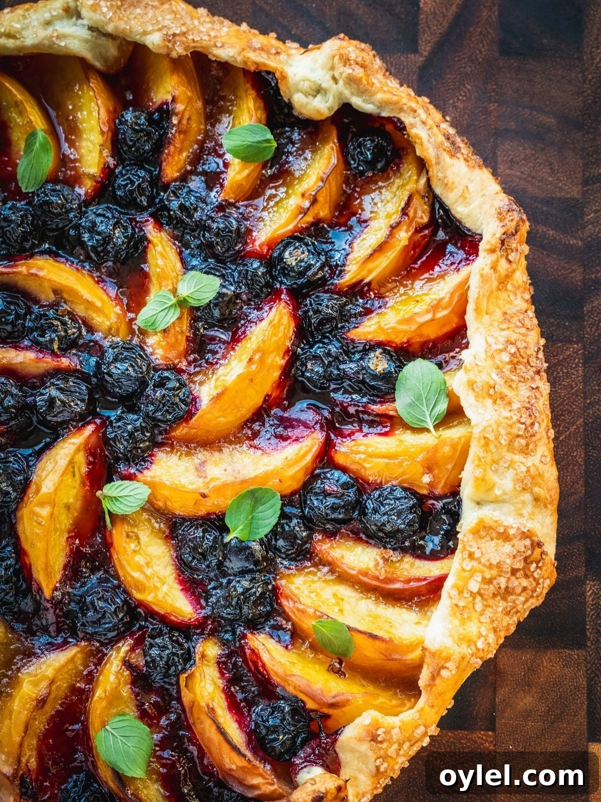 Blueberry Peach Galette Recipe with Lime and Brown Sugar 8 Blueberry Peach Galette garnished with mint on a wooden board.