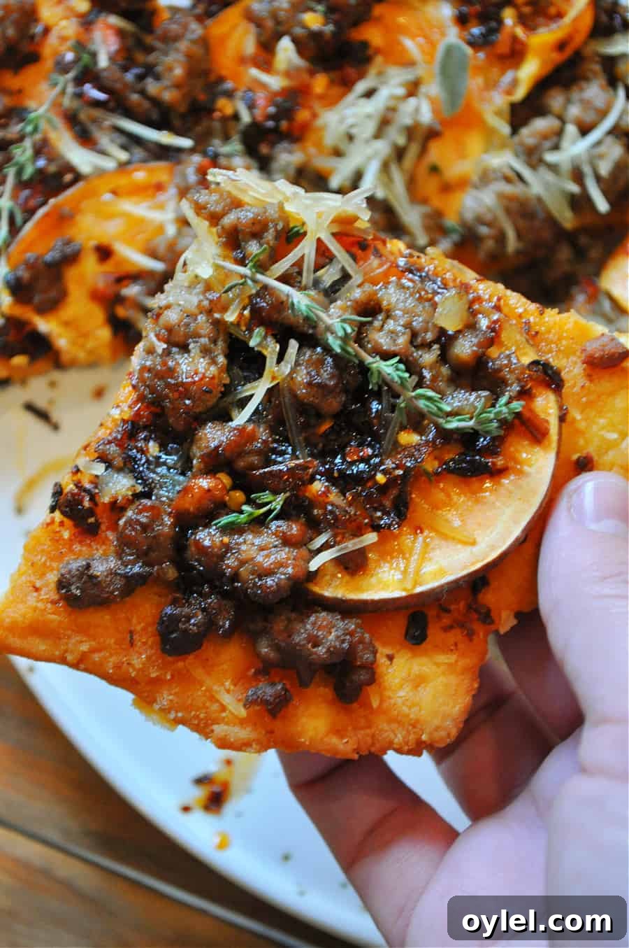 Close-up of flatbread topped with sweet potatoes, vegan sausage and chili crisp