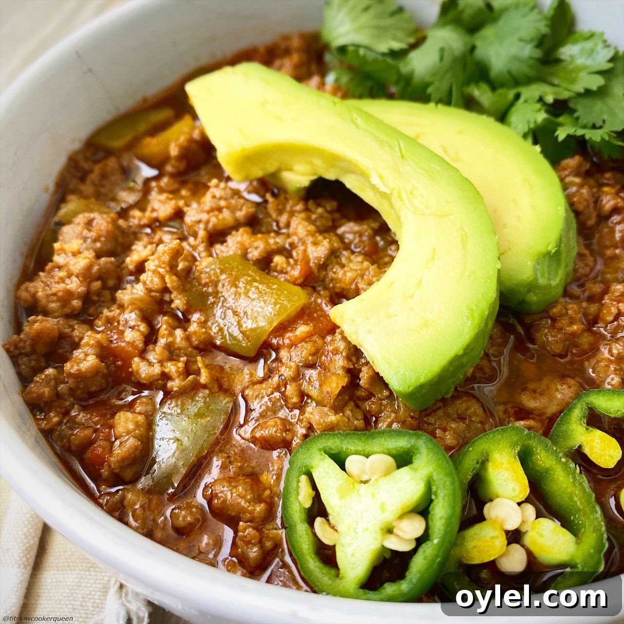 slow up side view of 'bean-free chili in a bowl with jalapeno, cilantro, and avocado on top