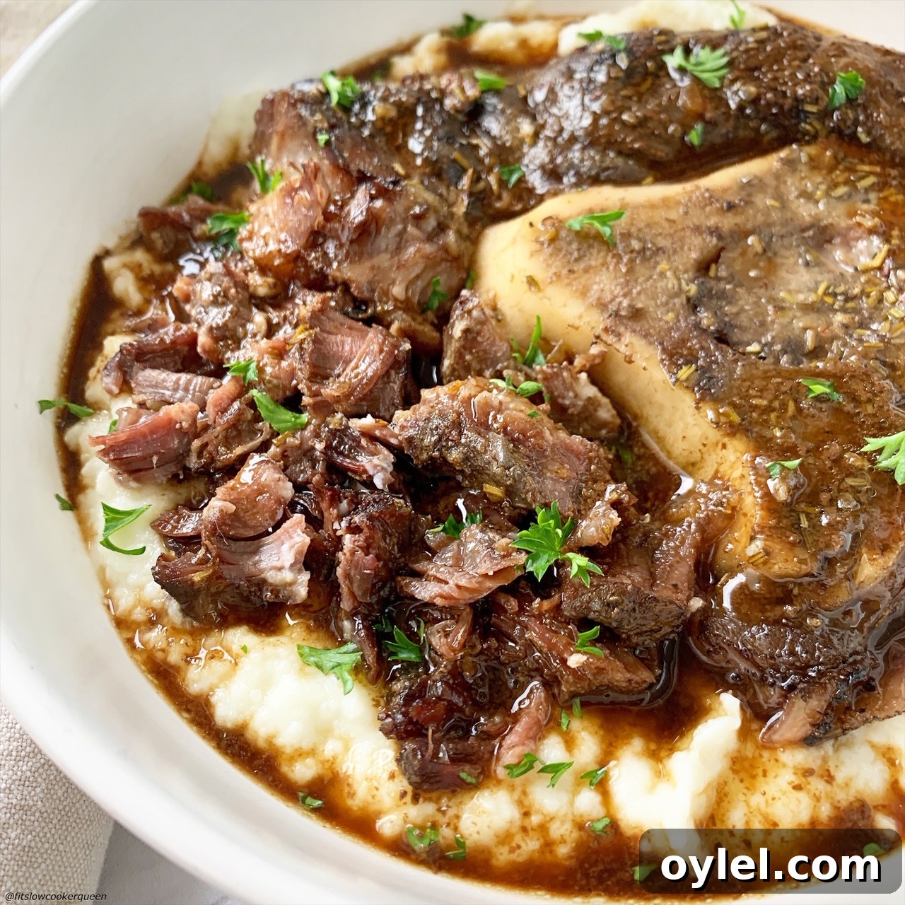 close up of booked beef shanks with broth served over mashed potatoes