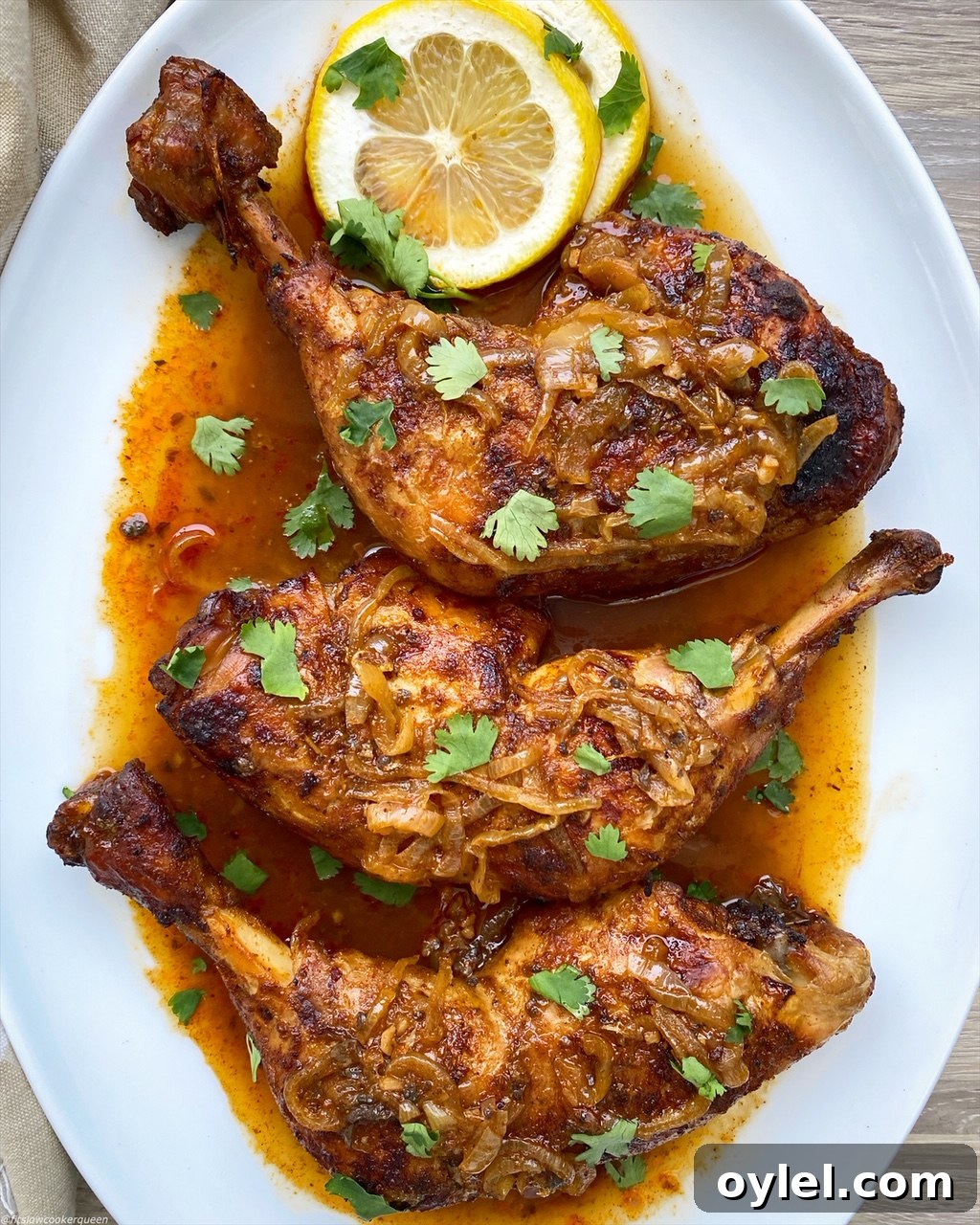 cooked piri piri chicken quarters after being broiled on a white plate with fresh cilantro on top