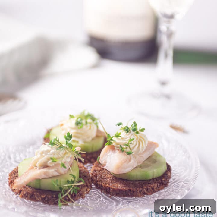 three smoked trout snacks with cucumber and rye bread on a glass plate
