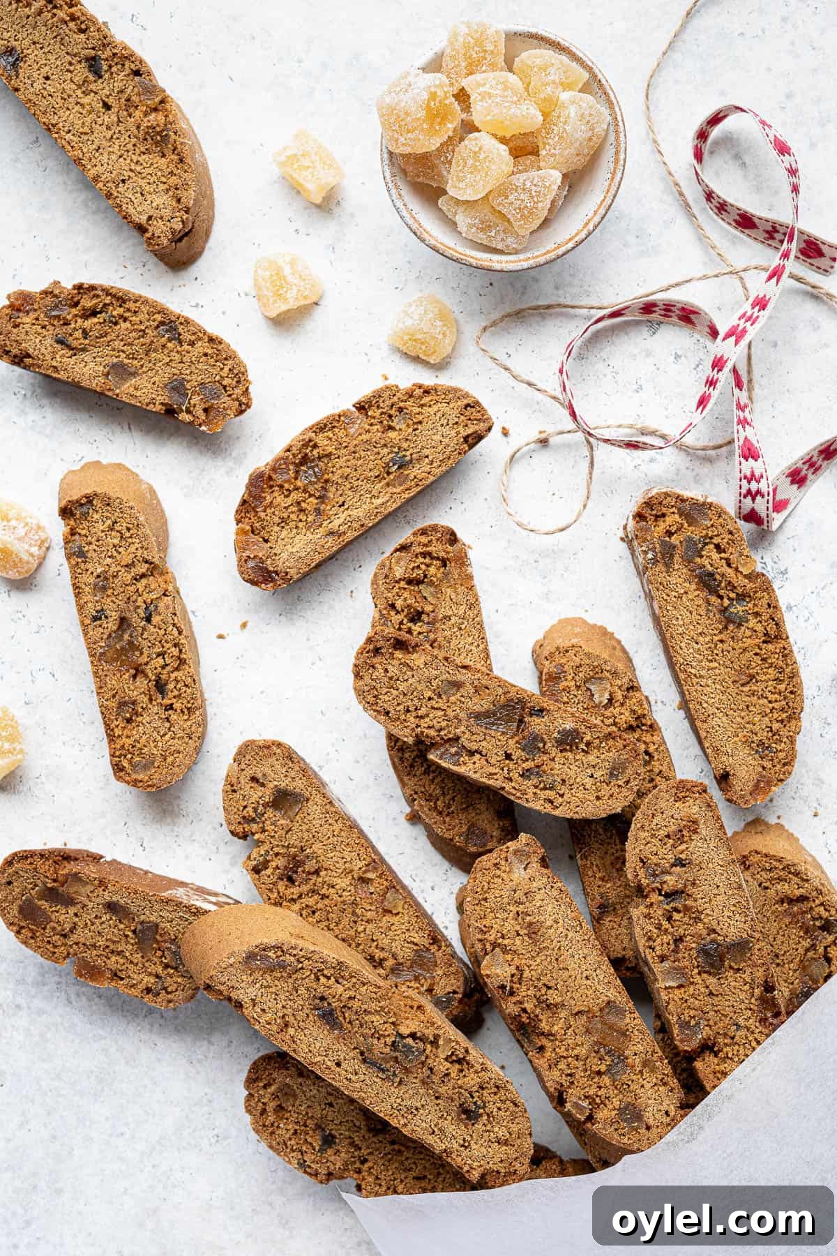 Vegan ginger biscotti in a white bag with a bowl of ginger and ribbons.