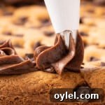 How to Make a Chocolate Chip Cookie Cake 14 piping chocolate frosting onto cookie cake