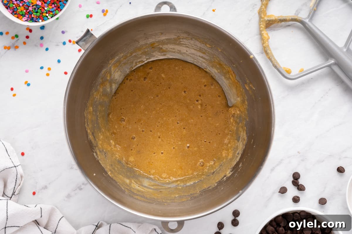 How to Make a Chocolate Chip Cookie Cake 18 wet ingredients for chocolate chip cookie cake in a metal bowl