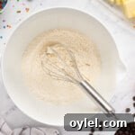 How to Make a Chocolate Chip Cookie Cake 6 dry ingredients in a white bowl with a whisk