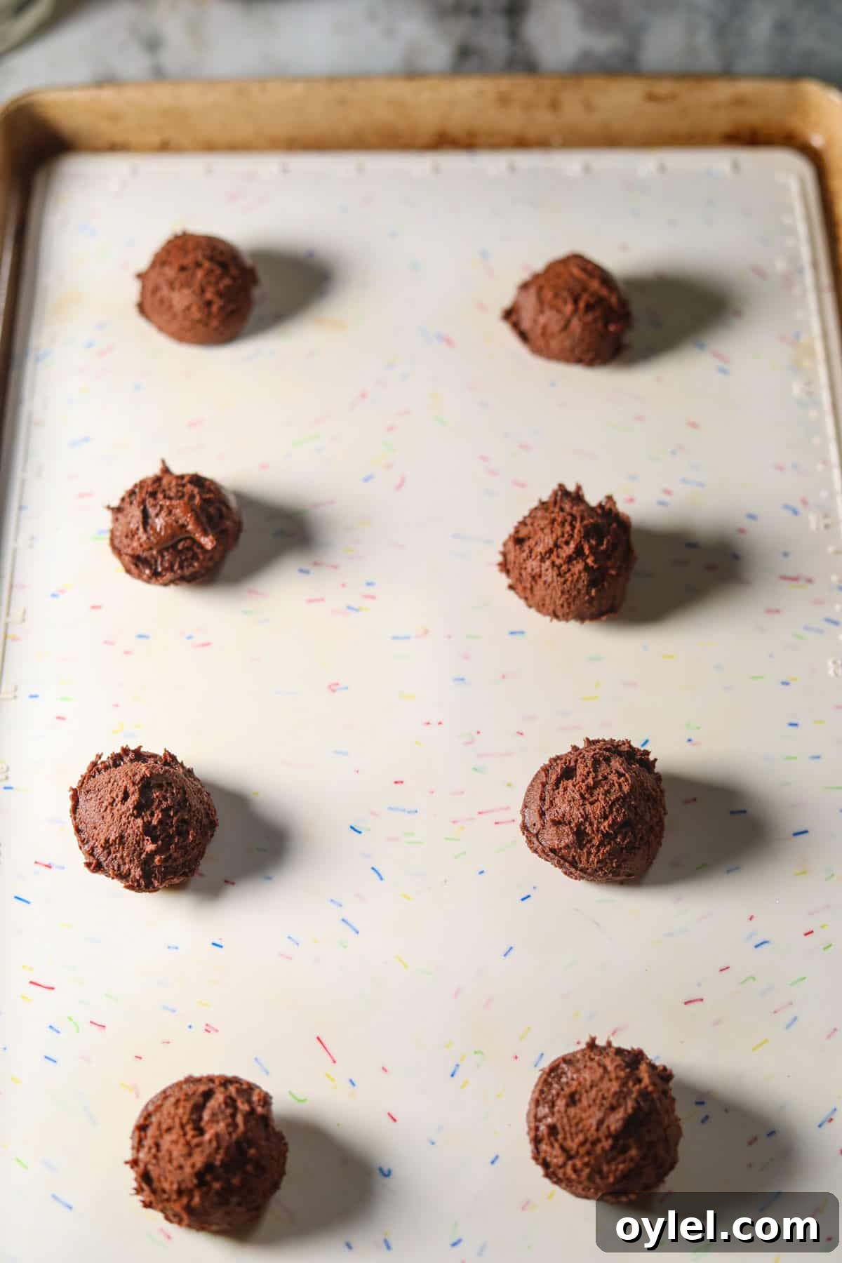 Peppermint bark cookie dough balls on a baking sheet before going in the oven.