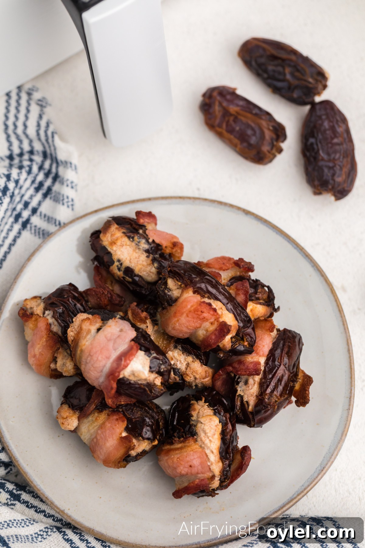 Air Fryer Bacon-Wrapped Dates Recipe 2 Overhead photo of cream cheesed stuffed bacon wrapped dates on a plate.